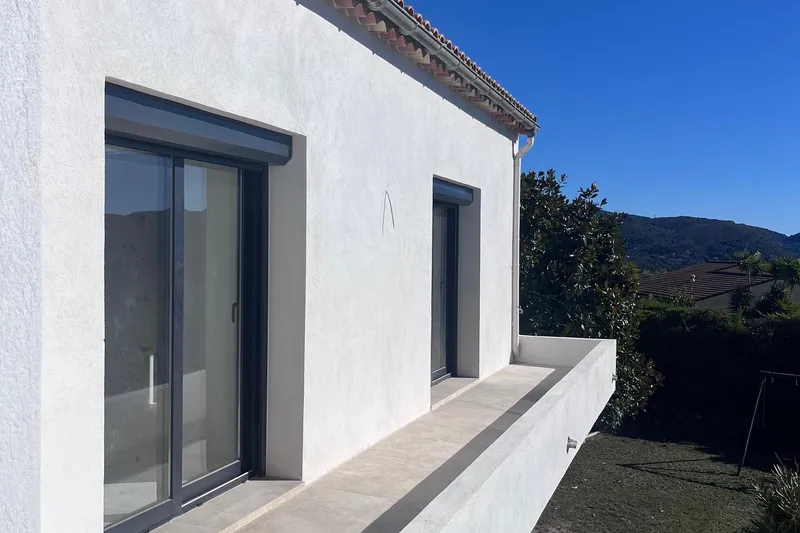 Façade blanche d'une villa contemporaine avec baie vitrée, après travaux